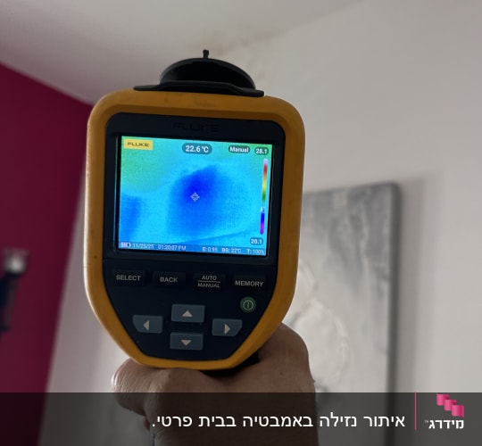 מד חום אינפרא אדום מציג טמפרטורה על קיר